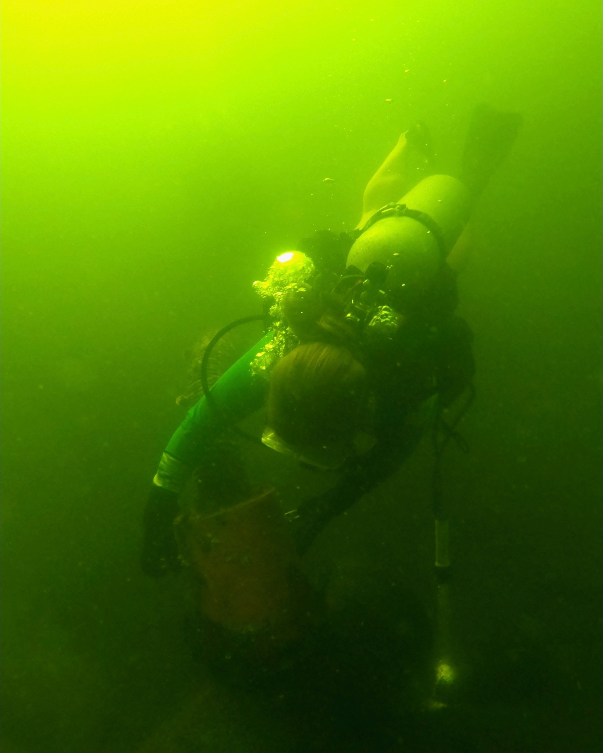 a woman scuba dives in murky greenish water