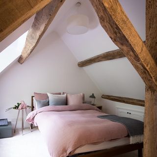 attic bedroom with white wall and wooden beam