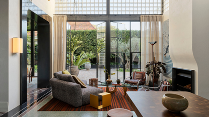 a contemporary living room with a sculptural fireplace and steel glass french doors