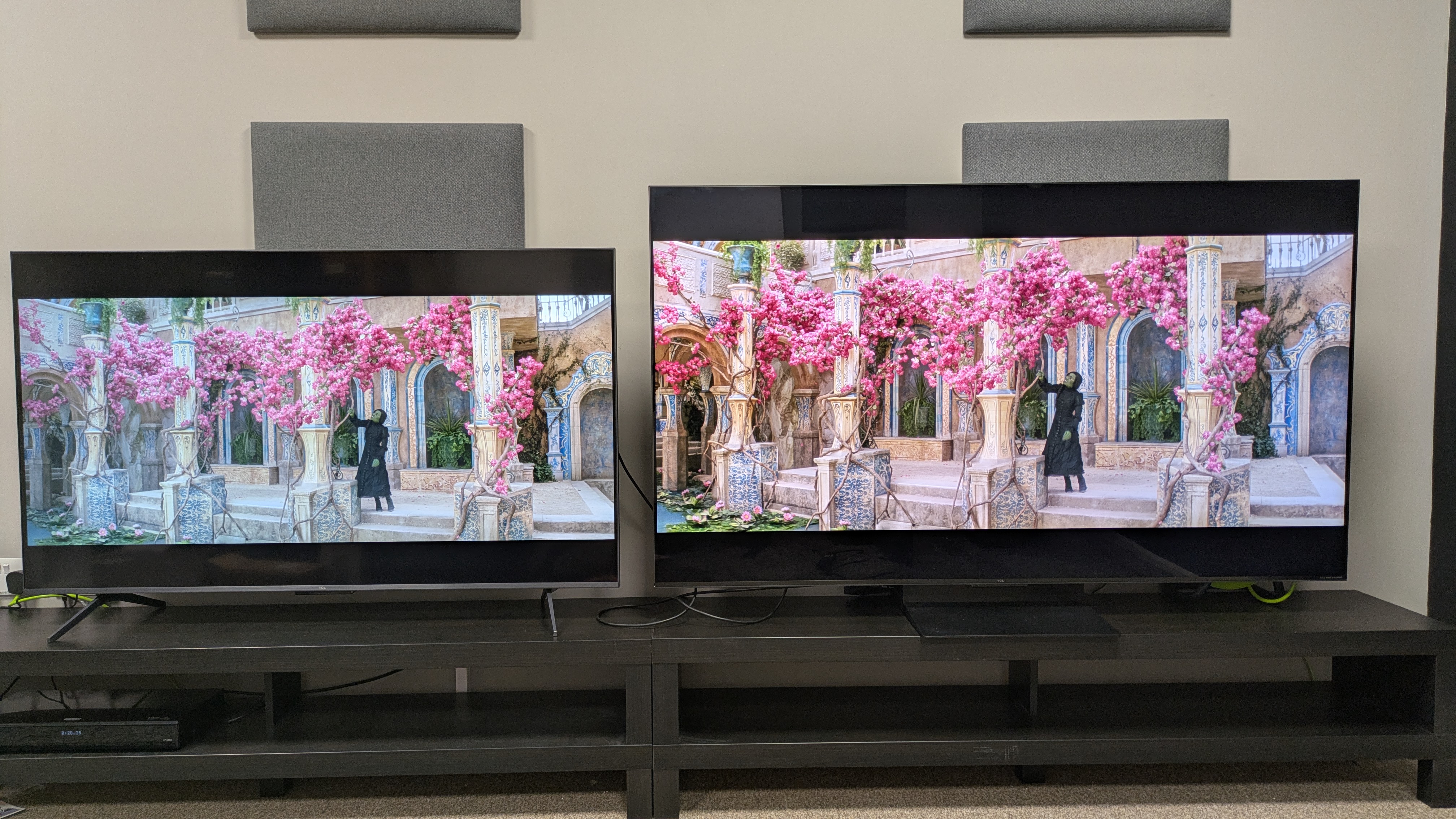 TCL C6K (left) and TCL C7K (right) showing Wicked on screen, with Elphaba among some pink flowers