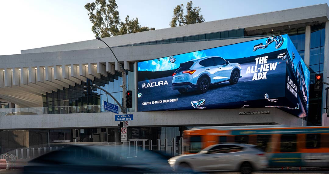 A billboard lights up the Sunset Strip as car lights zoom by.