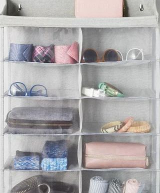 A gray over-the-door organizer with colorful glasses, scarves, ties, and accessories in it