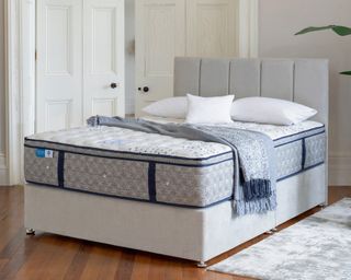 A Vitality Visco Double Mattress on a bedframe with grey upholstered headboard