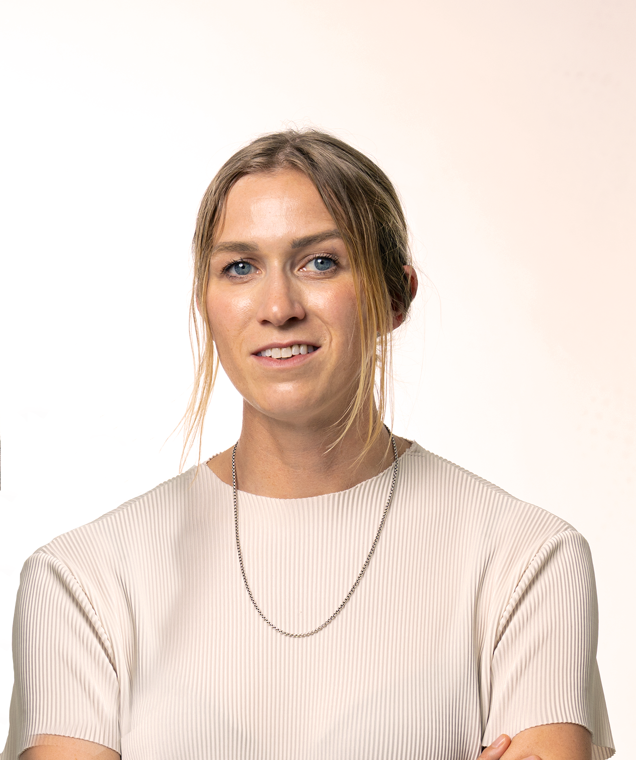 woman with blonde hair and a cream top with a necklace