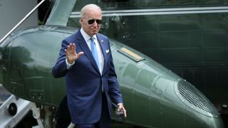 US president Joe Biden walking in front of a helicopter and waving at the camera