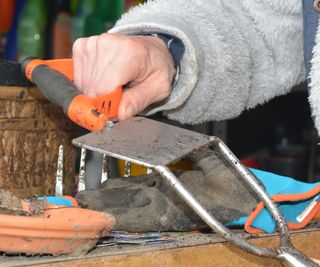 A woman's hand sharpening a hoe blade after use