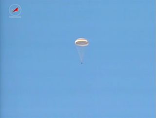 The Soyuz TMA-09M space capsule carrying the Expedition 37 crew and Olympic torch back to Earth is seen descending under parachute during a Nov. 10, 2013 landing EST in Kazakhstan, where the local time was Nov. 11.