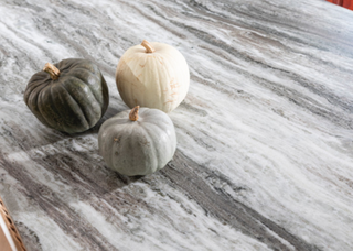 a close up of a leathered stone work surface with three mini pumpkins on it