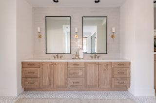 Couples bathroom in white with modern wooden cabinets and subtle Moroccan style floor tiling