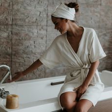 Young woman preparing a bath wearing a bathrobe