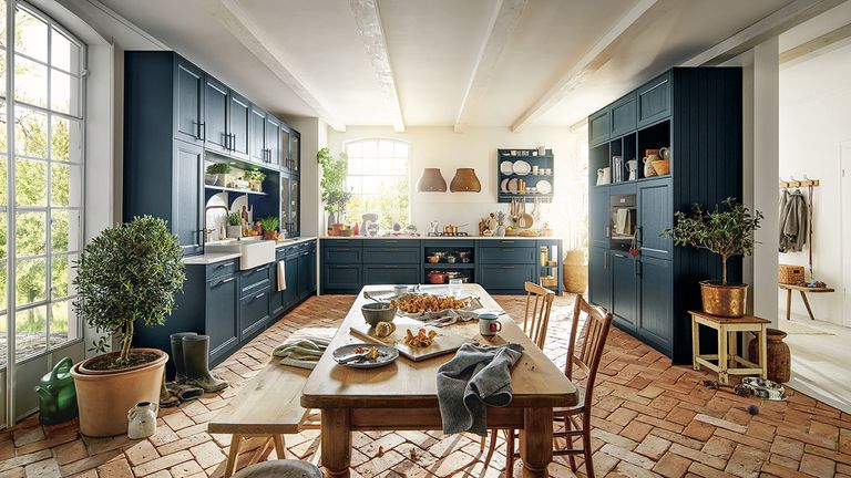 A picture demonstrating Kitchen trends 2022 showing open shelving, blue cabinetry and a rustic brick floor in a kitchen