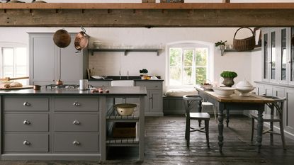 A large traditional kitchen with exposed wood ceiling beans, a large kitchen island, a dining table, and gray cabinetry