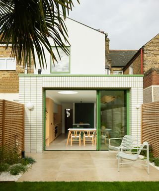 white rear brick extension with green sliding patio doors and green trim to roof