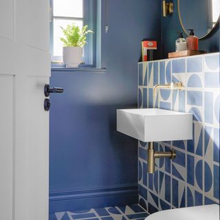 small bathroom with painted blue walls and blue and white patterned floor and wall tiles