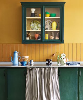 A yellow kitchen with a green sink and cabinet