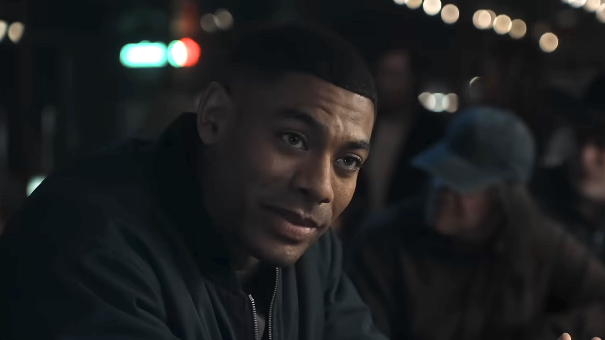 John Stewart smiling in a bar in the Lanterns trailer.