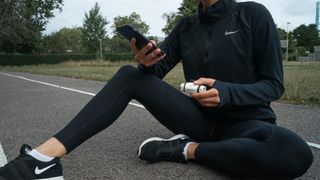 Person holding the Airofit outdoors on a running track while sitting down with right knee bent