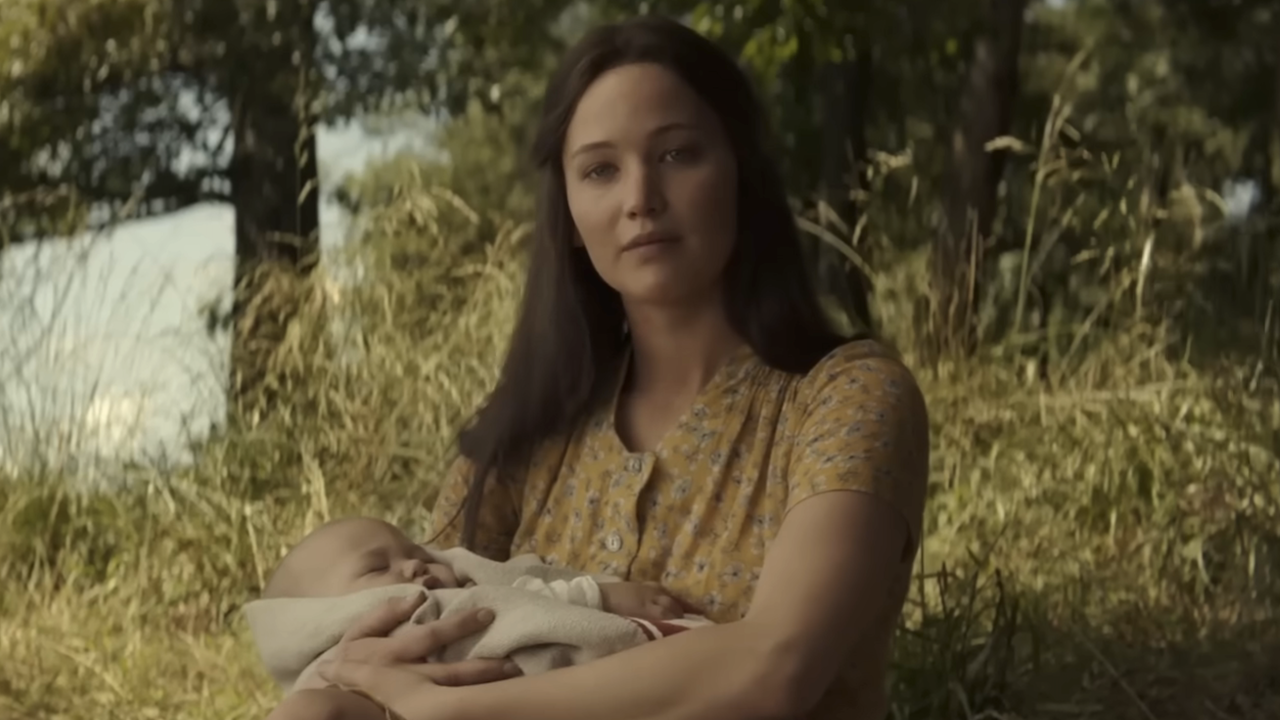 Jennifer Lawrence&#039;s Katniss Everdeen holding a baby while outdoors at the end of Hunger Games: Mockingjay Part 2
