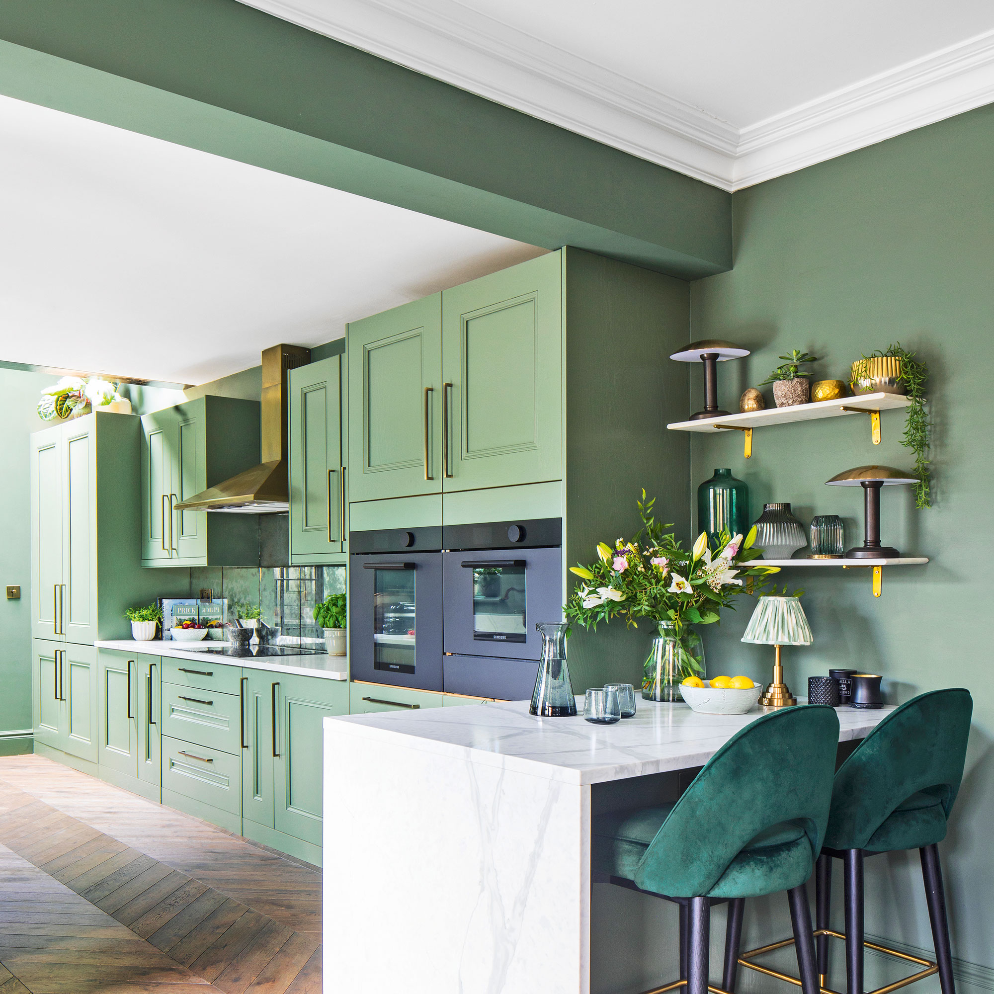 Green walls with green kitchen cabinets and white marble waterfall breakfast bar