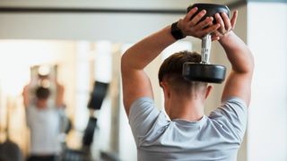 man doing tricep extension exercise with dumbbell