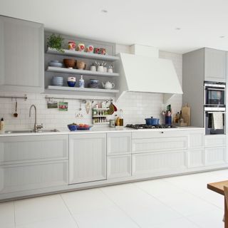kitchen with white floor and wall tiles grey panelled-look cupboards and eye-level ovens
