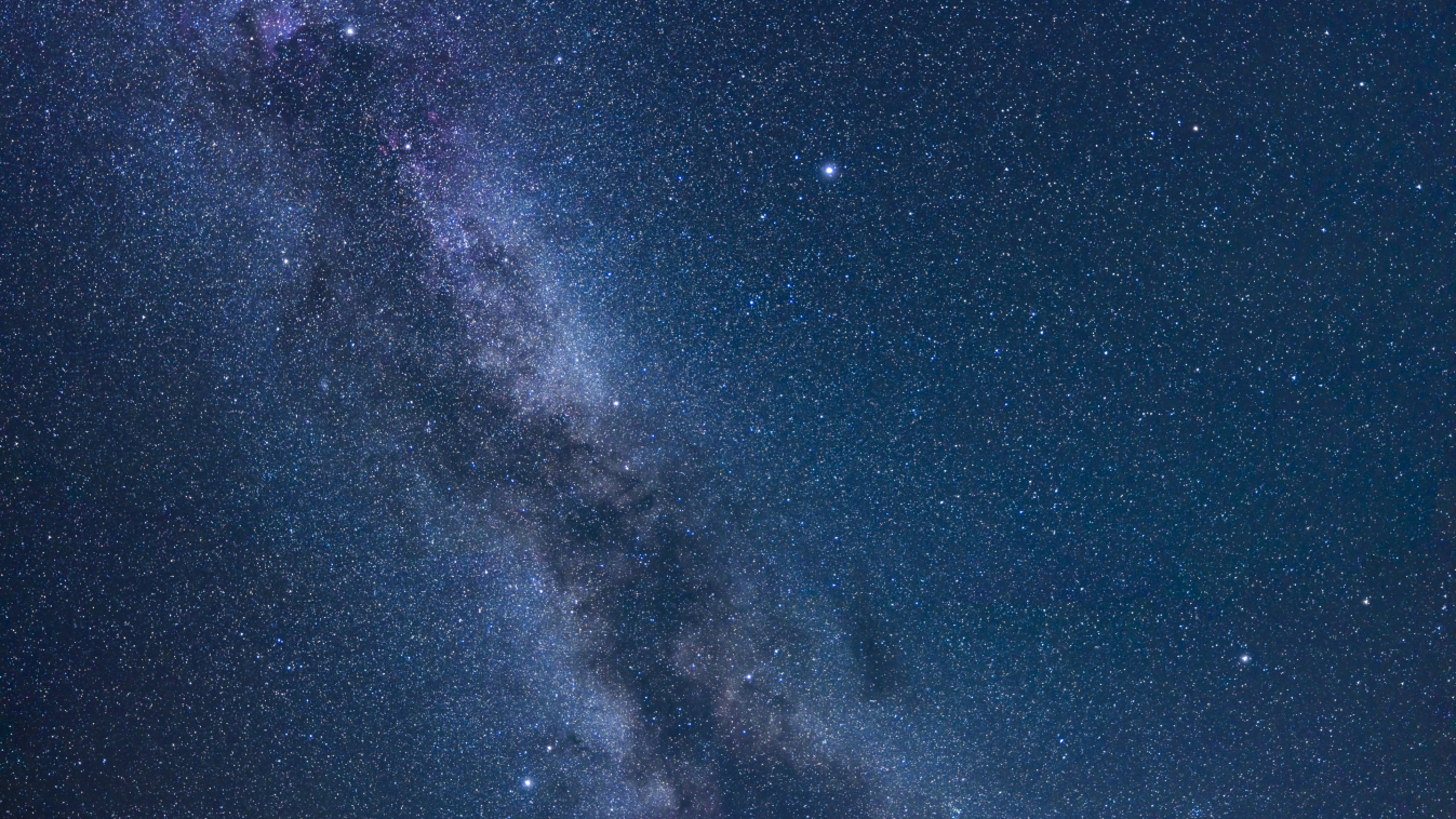 A photograph of a starry night sky showing the glowing band on the milky way passing through a triangular formation of three bright stars.
