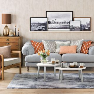 Neutral living room with brown accents and grey sofa with picture ledge above