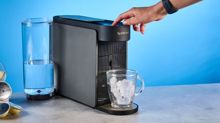 the nespresso vertuo up machine photographed against a blue background