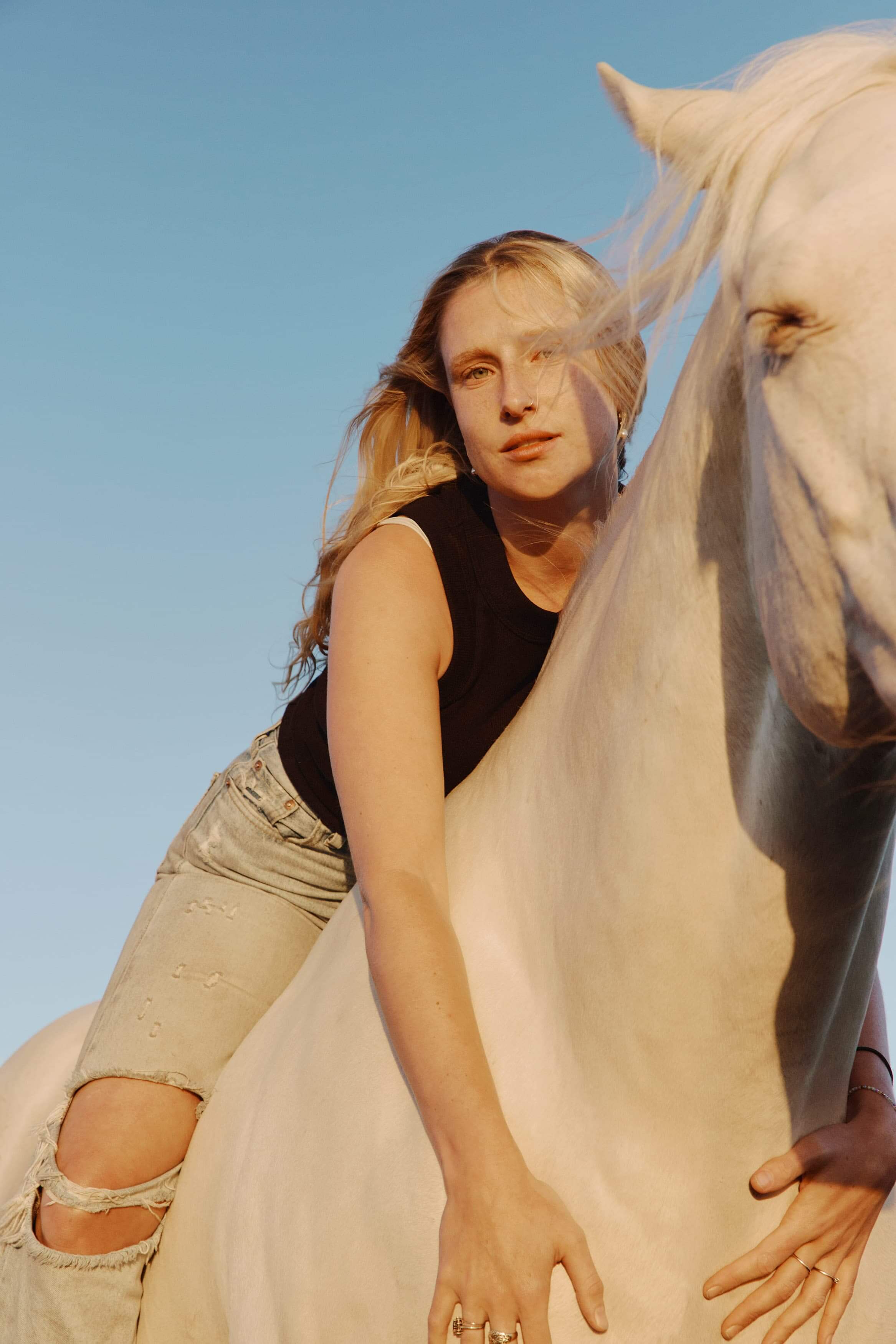 British singer Billie Marten sitting atop a white horse.