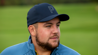 A golfer poses in a Puma DRYLBL Storm Golf Cap