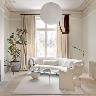 White living room with white rounded sofa and plastic coffee table