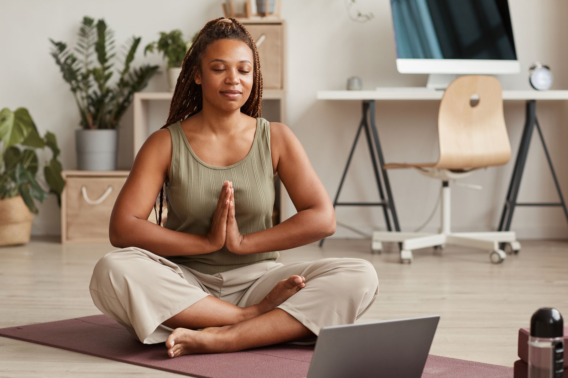 Pilates vs yoga: Woman in lotus position meditating at home