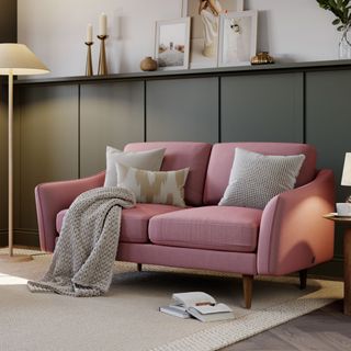 Pink sofa next to lamp with grey throw and cushions