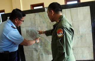 Indonesian airforce officers check the map as they prepare for a search operation for the missing flight MH370 over the Malacca strait.