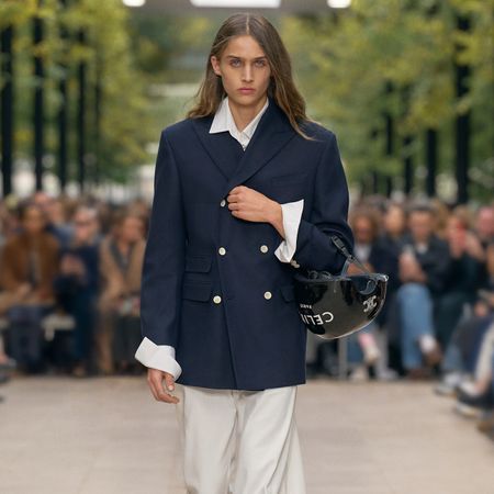 Model on the Celine S/S 26 runway wears structured double breasted jacket, wide leg white pants and Celine ballet lace up shoes.