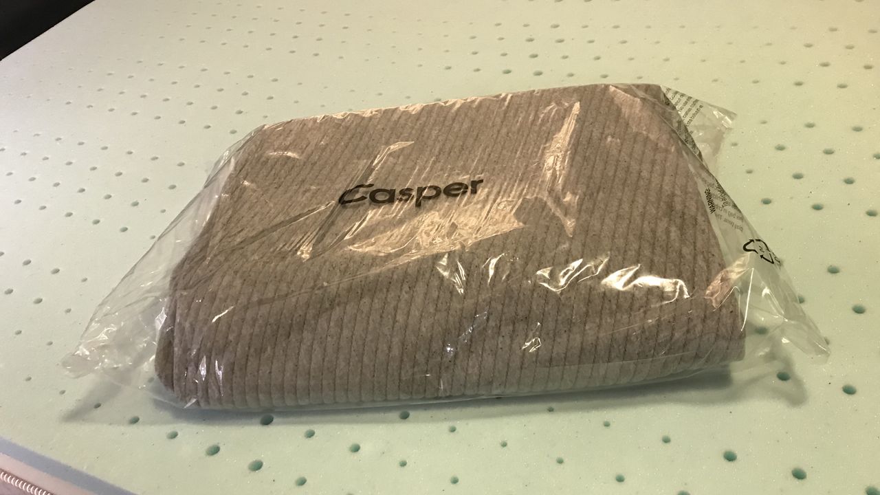 The Casper Comfy Mattress Topper's cover still in its plastic packaging.