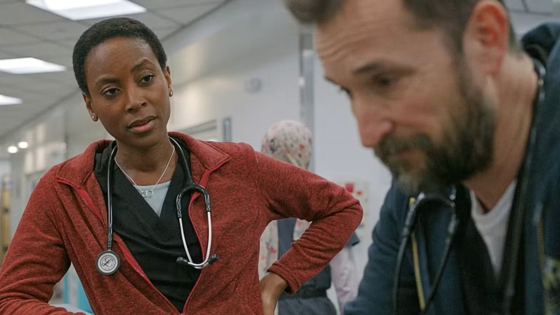 Dr. Collins stands over Dr. Robbie, talking to him