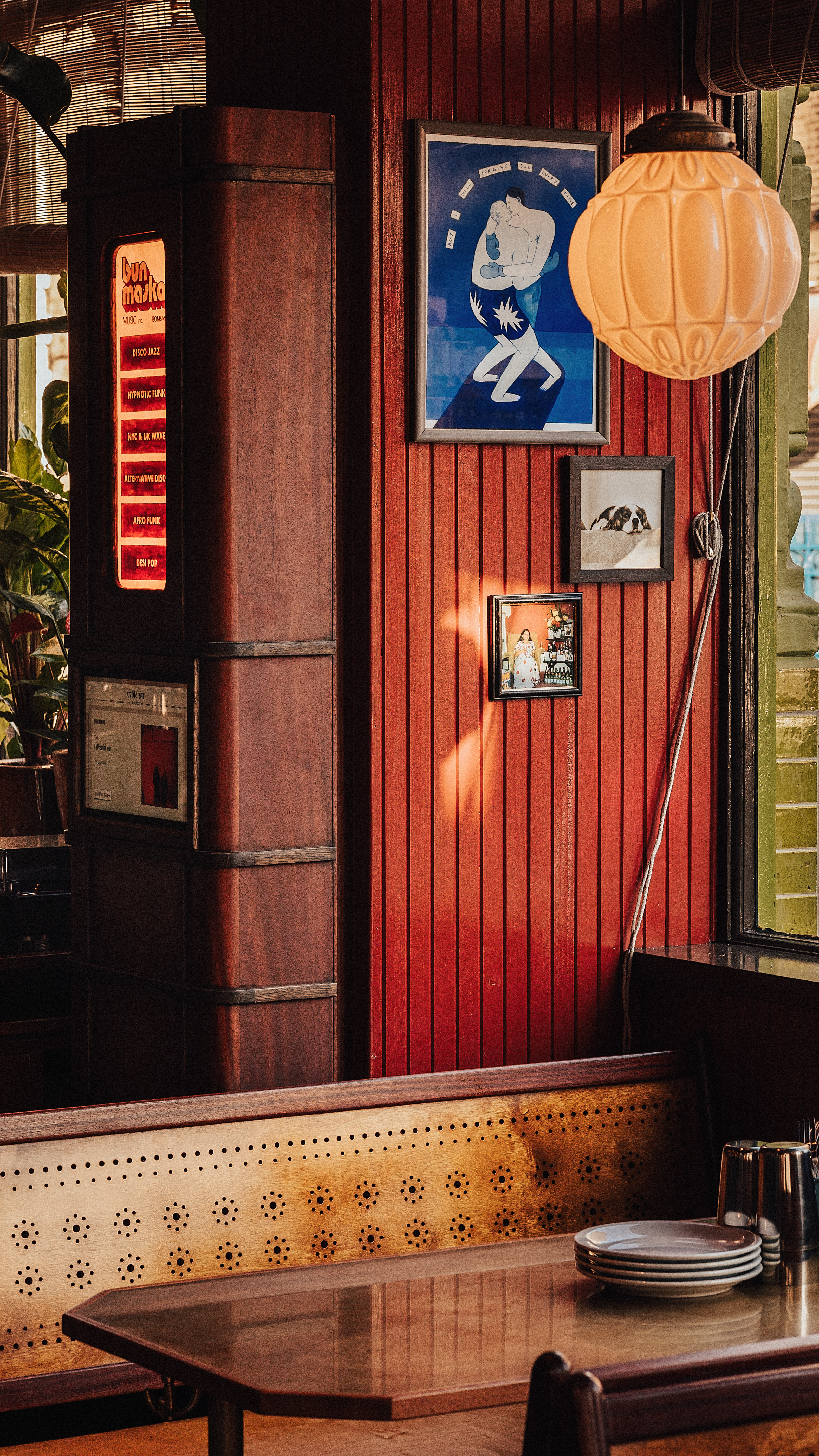 A Bombay-inspired restaurant with rooms features a retro-fueled aesthetic characterized by warm, earthy tones, sleek and textural surfaces.