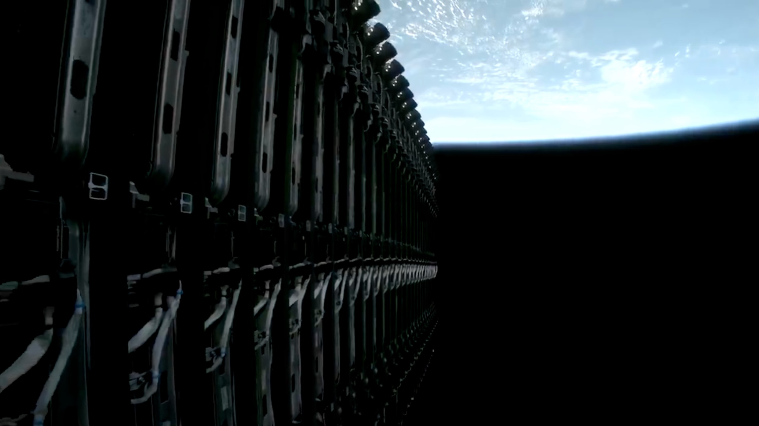 A stack of several dozen flat satellites arrayed on the upper stage of a rocket with earth in the background