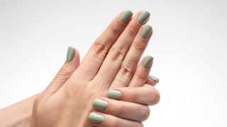 A hand with a light green manicure