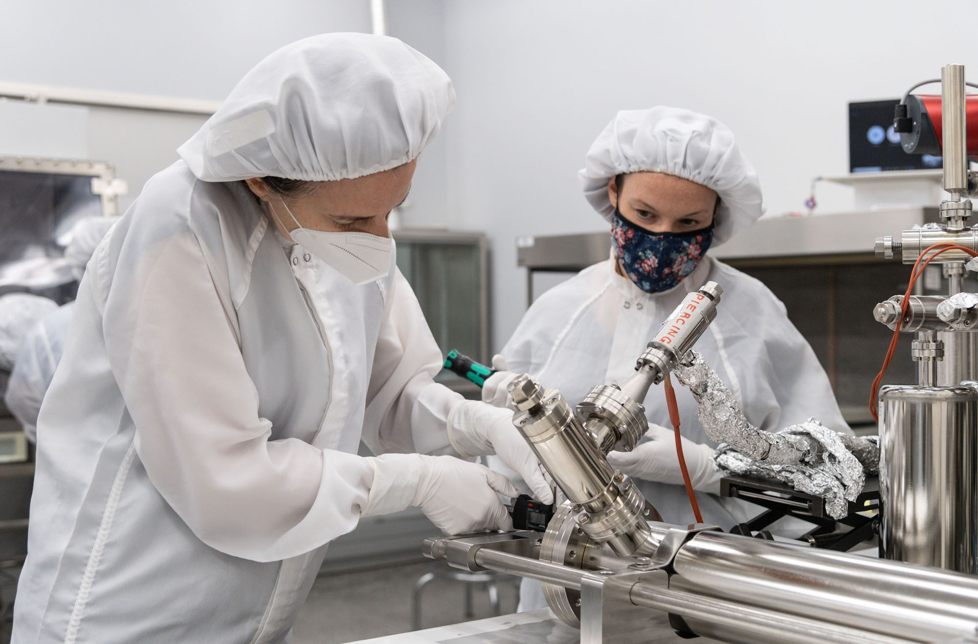 From left, Dr. Juliane Gross, Astromaterials Research and Exploration Science Division (ARES) deputy Apollo curator, and Dr. Francesca McDonald, from ESA, take precise measurements from a piercing device prior to using a newly developed tool while opening samples from an Apollo 17 moon rock canister..