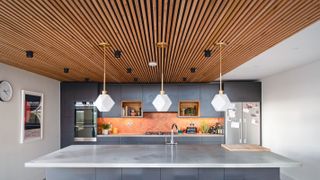 contemporary kitchen with pendants over island and timber ceiling cladding