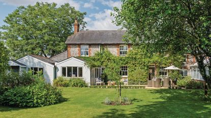 Brick and flint house with a slate roof, a modern extension and conservatory and mature garden.