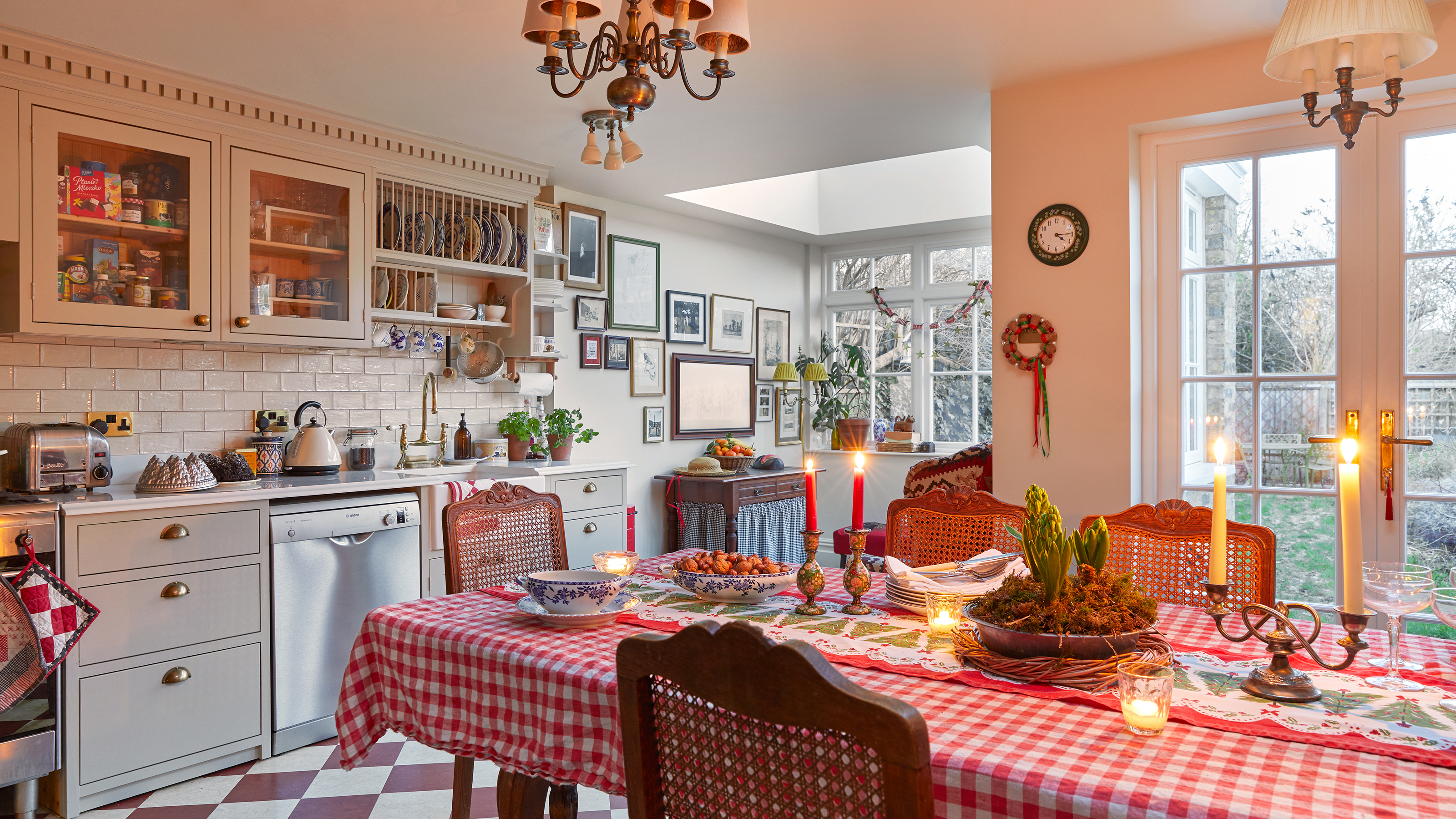 kitchen diner with table dressed with red and white gingham table cloth, candles and red and white chequered floor tiles