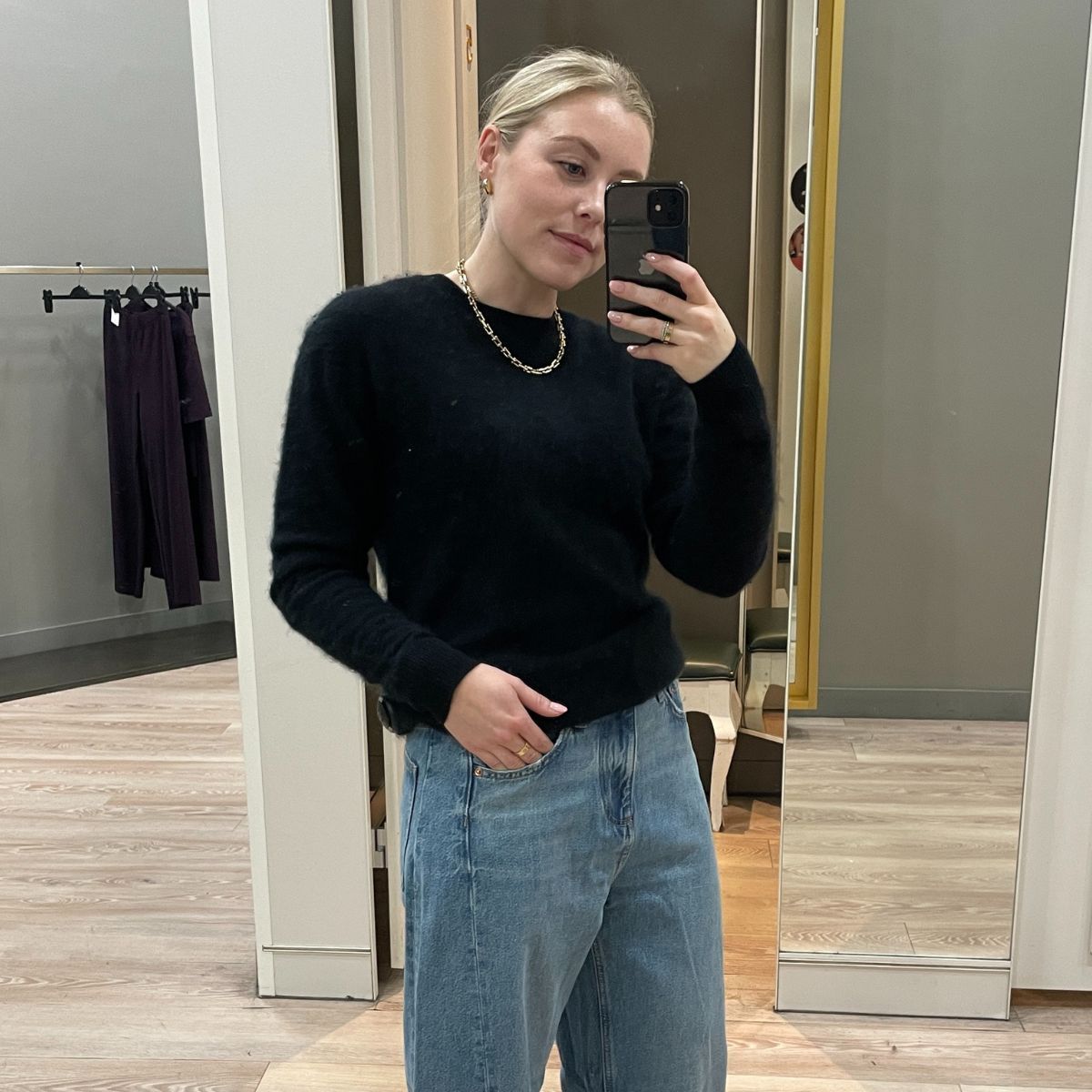 Woman wears black cashmere jumper and blue barrel leg jeans