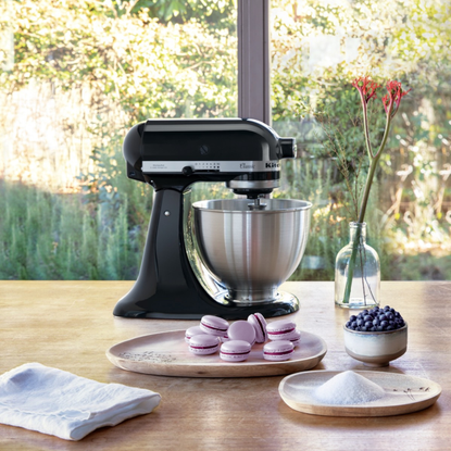 KitchenAid stand mixer in black next to a plate of pink macaroons.