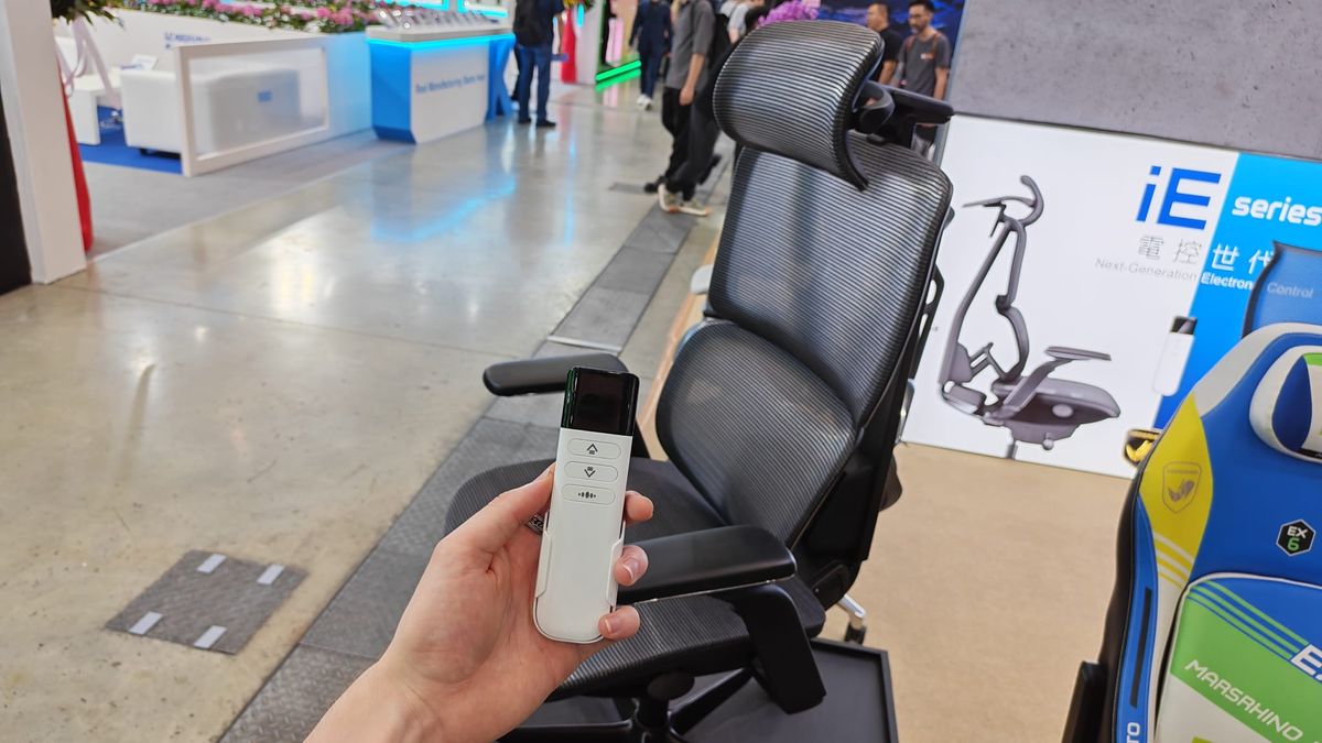 A reviewer holding the remote control for a MarsRhino gaming chair