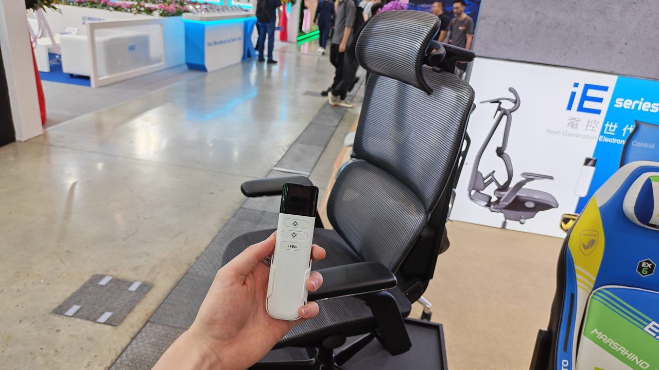 A reviewer holding the remote control for a MarsRhino gaming chair