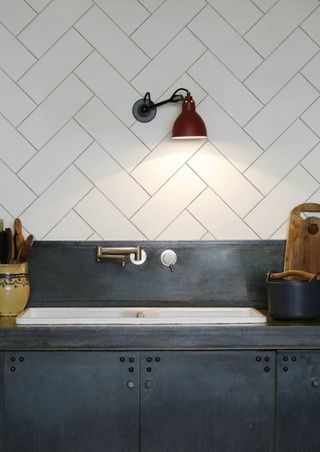 herringbone white metro tile effect wallpaper backsplash in a grey metal kitchen with brass accents from Lime Lace