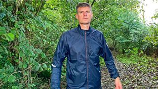 Man in woods wearing Salomon Sense Flow wind jacket
